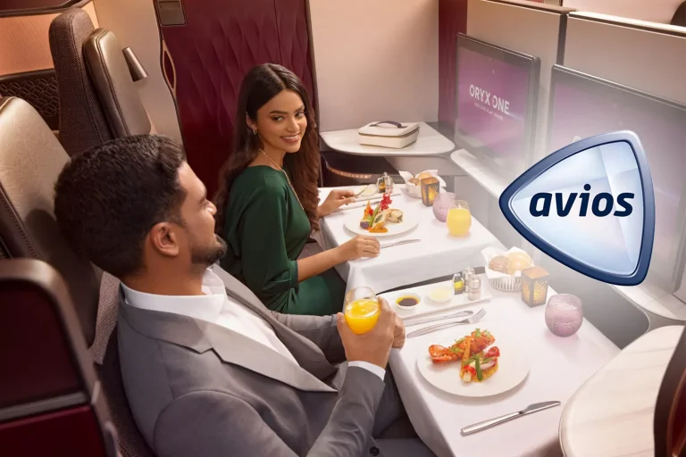 Couple in business class enjoying a gourmet meal on a long-haul flight, with drinks and elegant plating.