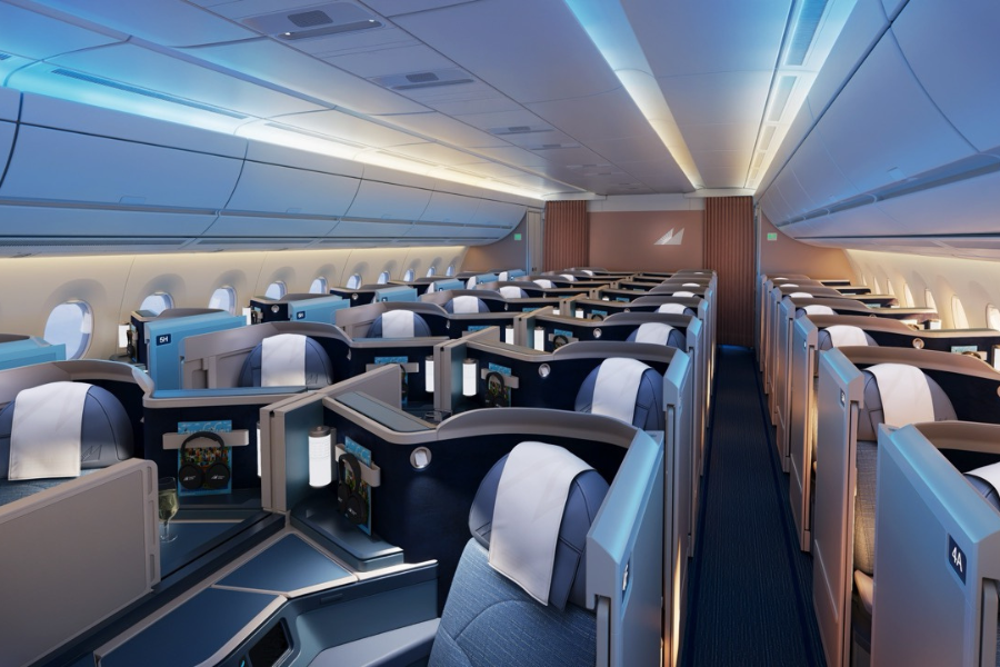 Wide view of a luxury airplane business-class cabin with private pods and blue-gray seating under cool overhead lighting.